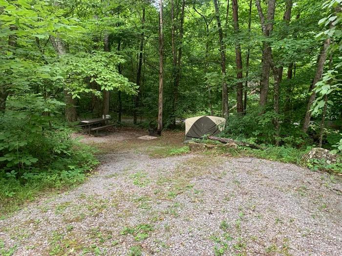 A gravel area with a brown and white tent.E-30 camping space.