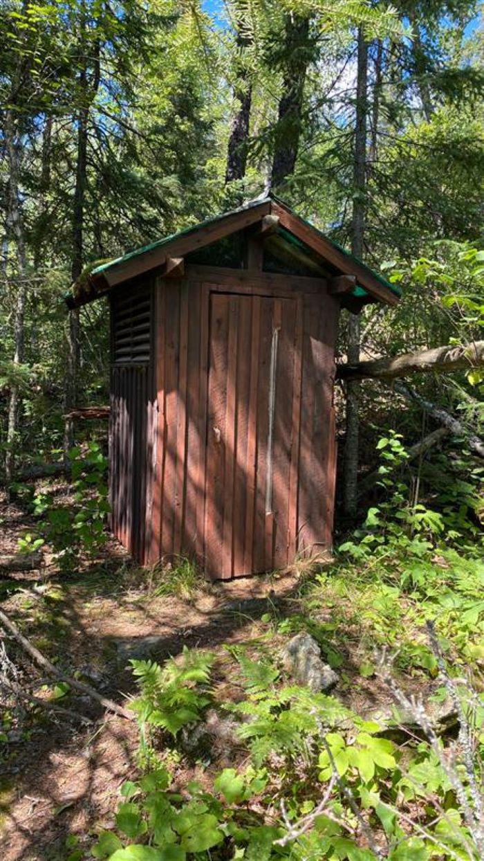 B1 - Agnes Lake, brown outhouse at campsite that is surrounded by trees.Outhouse at campsite