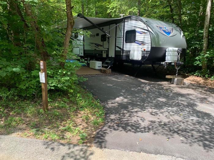 A blacktop area with a white and gray camper on the site.