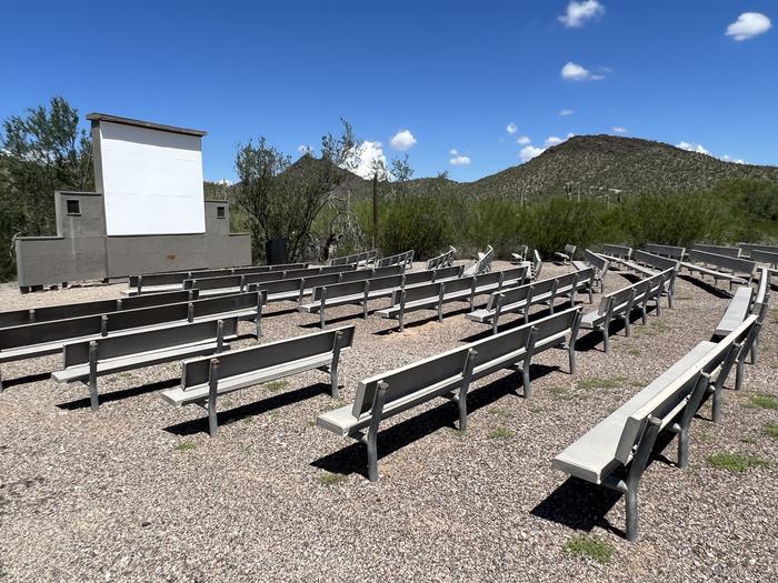 A photo of the amphitheater at TWIN PEAKS CAMPGROUND, with many benches and a screen.