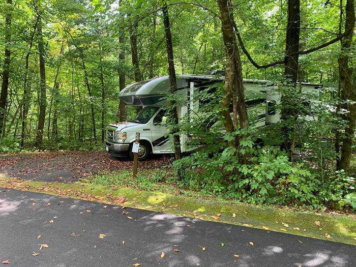 A blacktop pad with a white camper on the site.