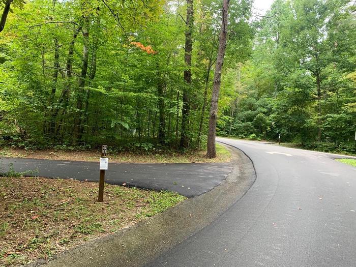 A blacktop road with a small brown post.C-23 camping space.