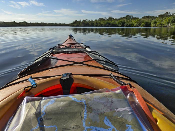 Looking towards the bow of an orange kayak. Water and trees in the background.Mapping your way through the Everglades backcountry