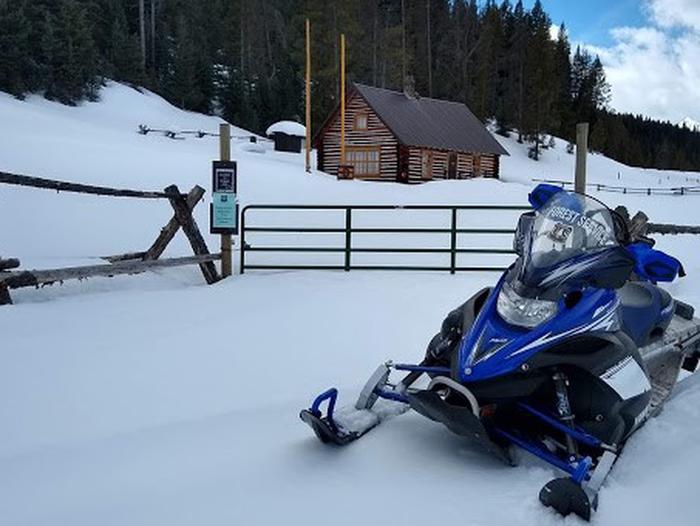 Snowmobile in front of cabin gate