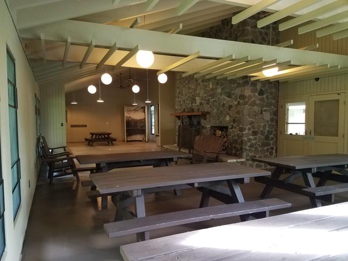 Inside of Clark Lake pavilion showing room layout with fireplace, benches, and picnic tables.Inside of the Clark Lake pavilion from the south end of the room.