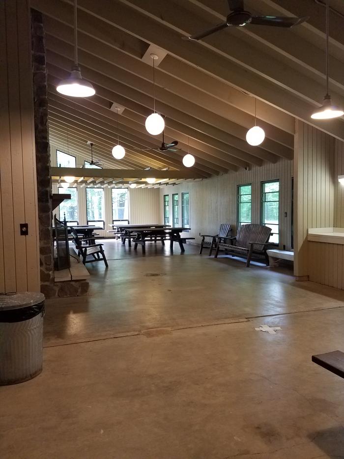 Inside of Clark Lake pavilion showing room layout with benches and picnic tables.Inside of the Clark Lake pavilion from the north end of the room.
