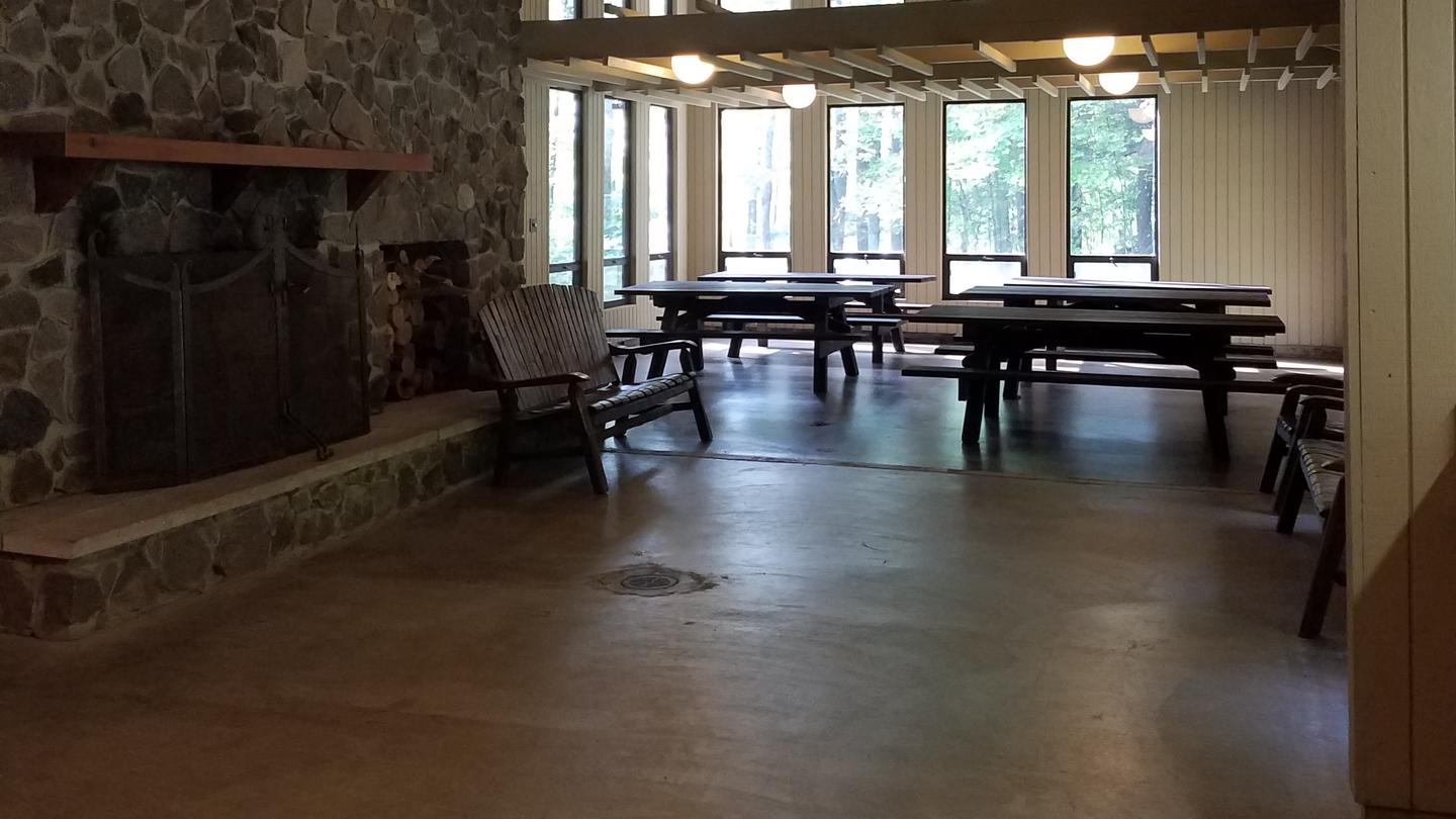 View of the inside of the Clark Lake pavilion with windows, bench, and picnic tables.Inside the Clark Lake pavilion.