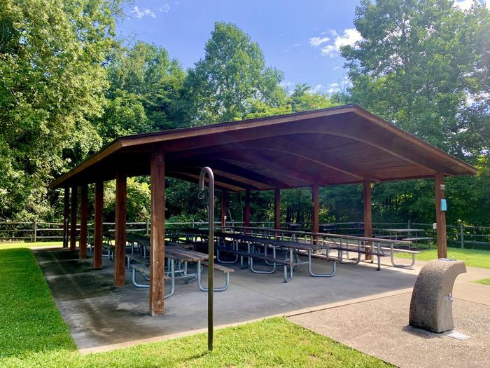 Brown wooden shelter filled with picnic wood and metal picnic sheltersInside of Redbud Picnic Shelter