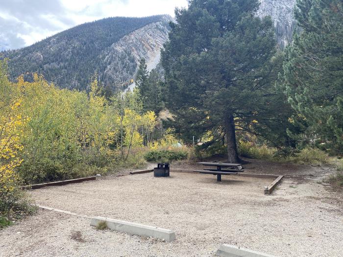 Campsite surrounded by trees with mountains in the backgroundA photo of Site 019 with Picnic Table, Fire Pit