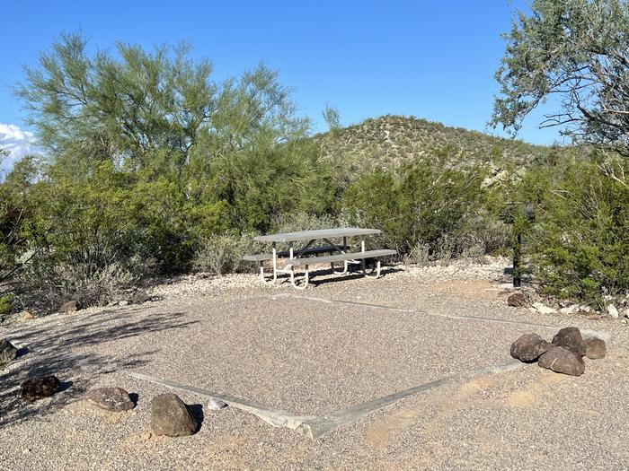 The large square tent pad of the site with the picnic table and grill.The tent pad of the site