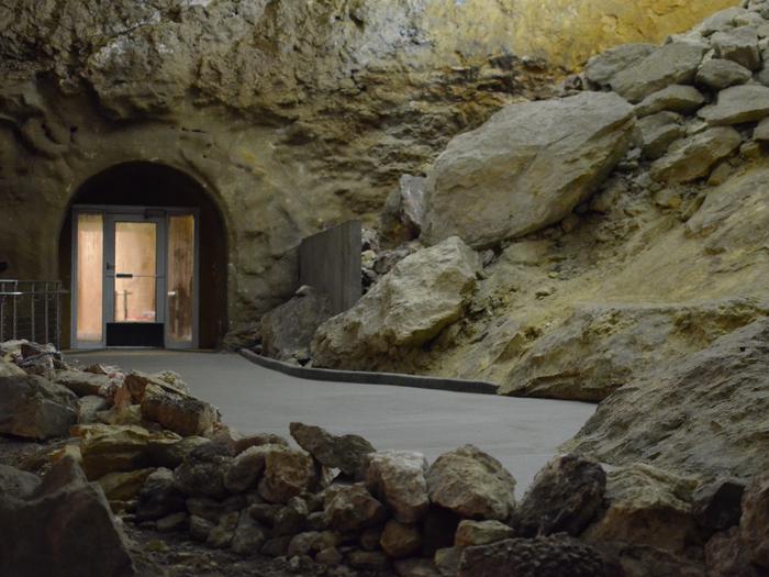 A large room inside a cave with elevator doors in the background.Explore the Target Room and learn about Jewel Cave on the Discovery Tour.