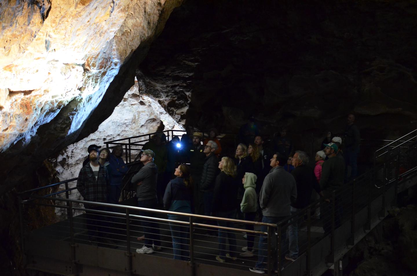 A tour group on a platform with a Park Ranger pointing out calcite crystals in a cave.On the Discovery Tour, visitors still have the opportunity to see some of the "jewels" of Jewel Cave.
