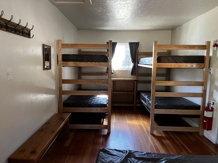 Bedroom showing double bed, two sets of bunkbeds and bench.Bedroom