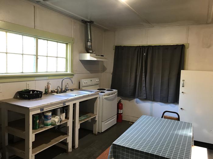 Dining and kitchen areaCabin rental includes an electric oven, cooking prep area, refrigerator, and dining table. 