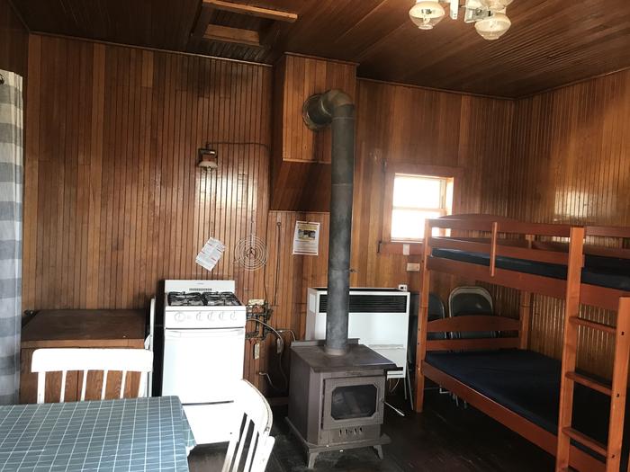 A cozy cabinThe main room serves as the kitchen and sleeping room with a wood stove, propane appliances and two bunk beds with mattresses. 