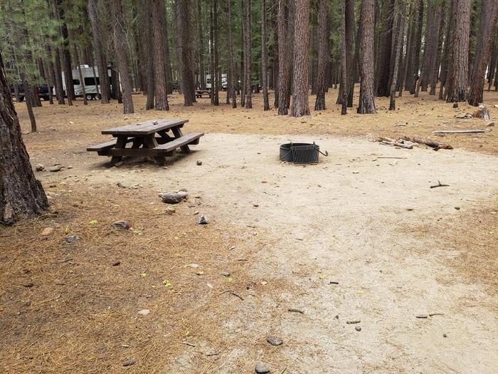 Spacious site with a grove of trees featuring a picnic table and fire ring.Lone Rock Site 48