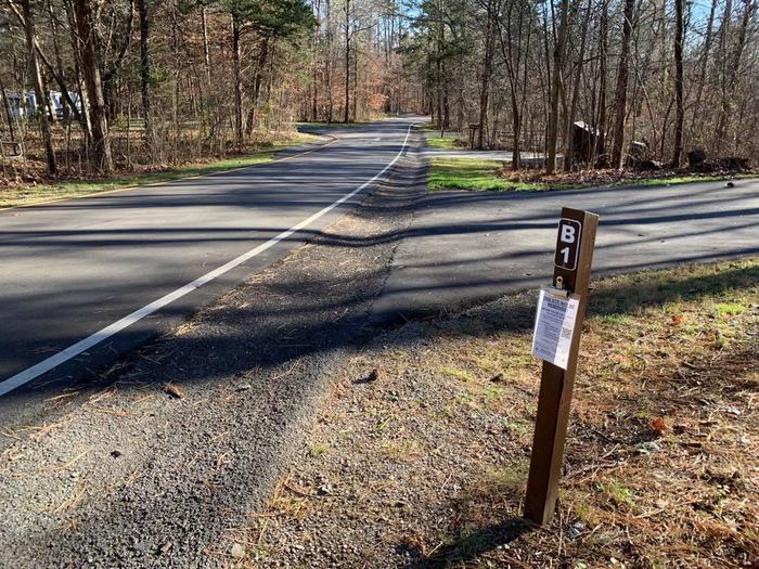 A small brown post with a blacktop road.B-1 campsite angle picture.