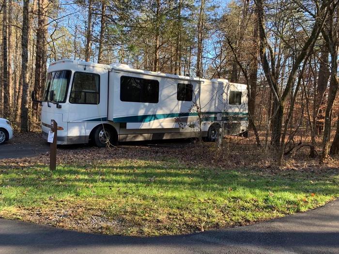 A white RV parked on the blacktop camping pad.