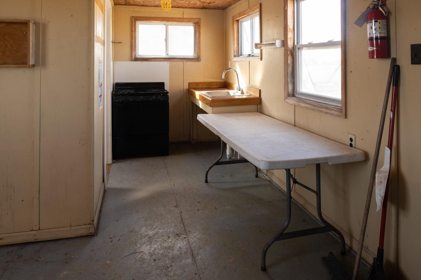 A view of the kitchen area, showing a table, sink, countertop, and propane range.Kitchen area.