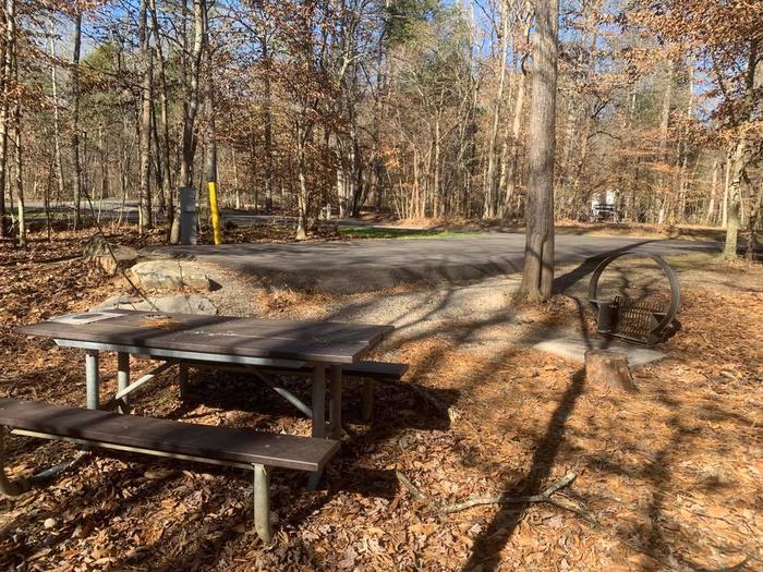 The end of a blacktop camping pad with a brown picnic table and brown circle fire ring.C-5 picnic table and circle fire ring.
