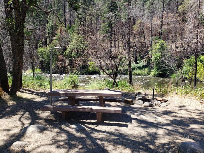 Shady site with a waterfront view which also features a picnic table, fire ring, lantern holder, and bear box.North Fork Site 4