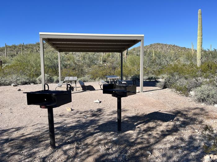 Two grills and two picnic tables with a shade shelter above it.All the cooking amenities are located next to each other.