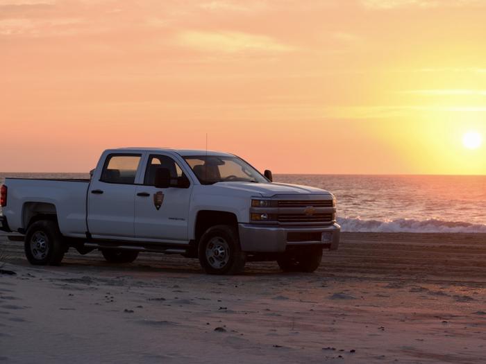 White NPS truck patrol beach at sunrise.NPS resource officers enjoy a beautiful sunrise while doing an early patrol to assess the resource.