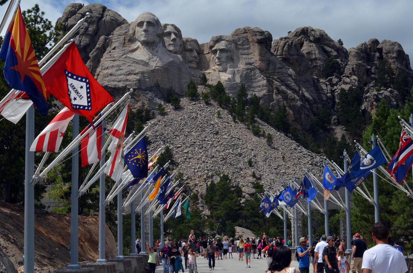 Mount Rushmore and the Avenue of FlagsVisitors walking along the Avenue of Flags with Mount Rushmore in the background.