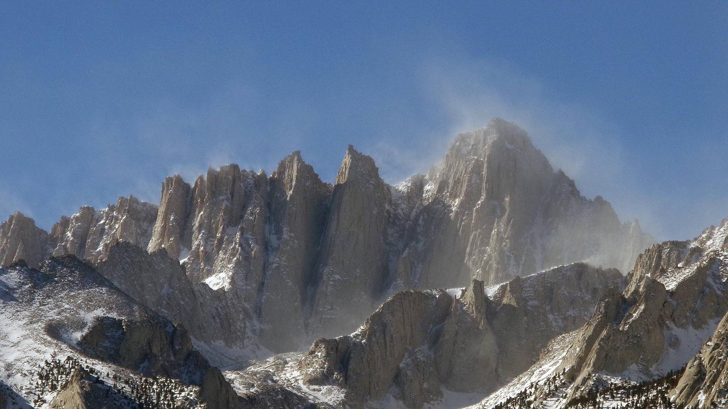 Wind blows snow from the summit of Mount Whitney.The beautiful veil of snow blowing from the summit also indicates the extreme conditions that may be encountered on Mount Whitney