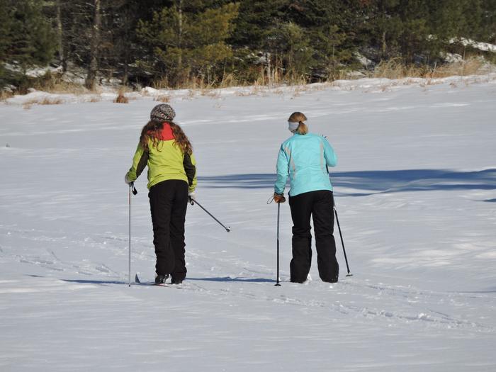 Two young women skiing across a frozen lake in Voyageurs National Park
