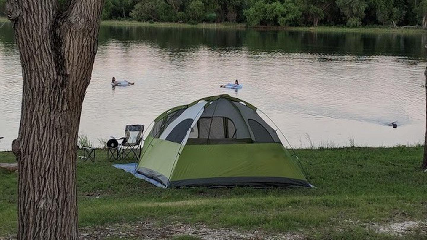 Green tent pitched on the shore of a lake.Tents at Plowman