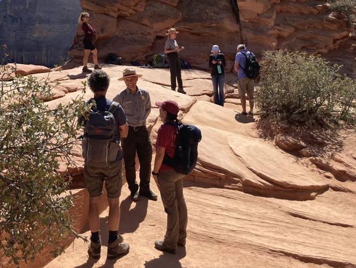 Rangers and hikers talk on a sandstone slabRangers Checking permits