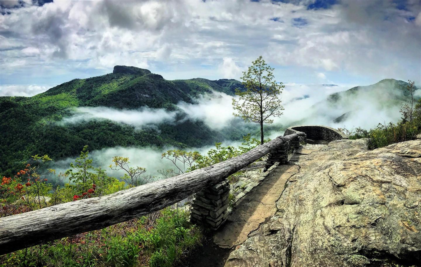 Rock surface with hand railing out to a cloudy mountain view. Scenic view of Table Rock Mountain looking south into the Linville Gorge from Wisemen's View. 