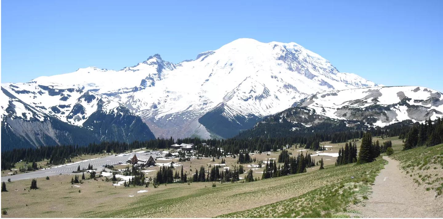 A panoramic view hiking on trail above the subalpine meadows of Sunrise with Mount Rainier in the background.Sunrise, one of the most beautiful places is the park is a short drive from the White River Campground. This view features the subalpine meadows of the Sunrise area in the foreground with snowcapped Mount Rainier in the background.