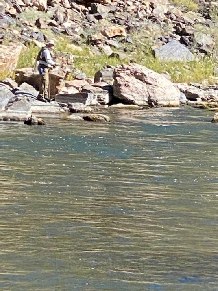 A man is fly-fishing along the rocky shoreline of Red Rock Canyon and the Gunnison River.The Gold Medal waters of Red Rock Canyon beckon.