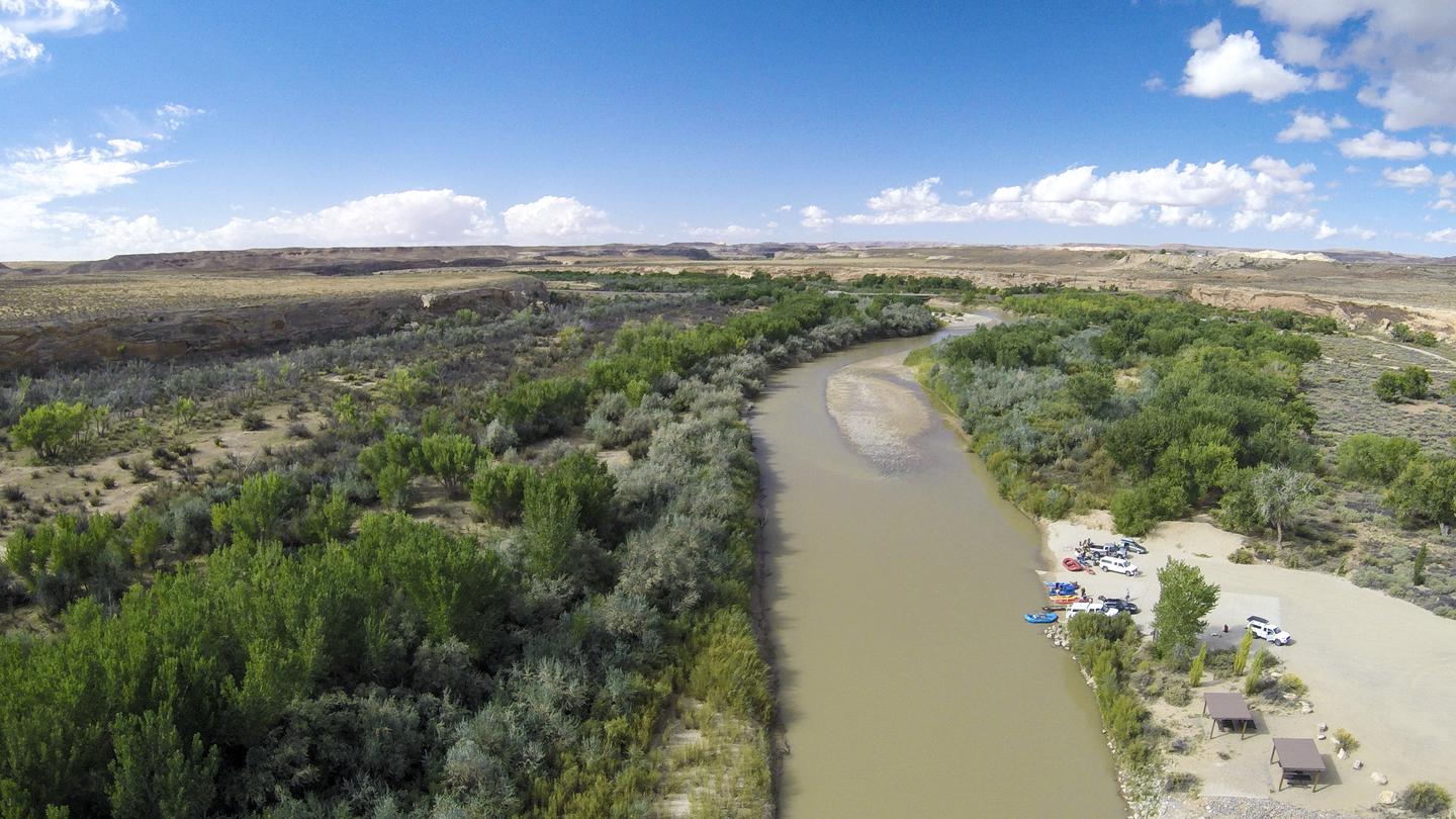 An aerial view of the San Juan River line with green cottonwood trees and the Sand Island boat launch area.Sand Island Recreation Area