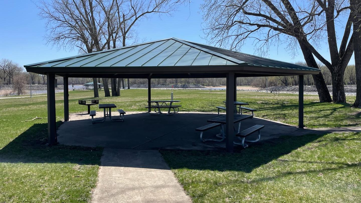 Large park shelter with picnic tables and grill. View of the Des Moines River in the background. North Tailwater Shelter
