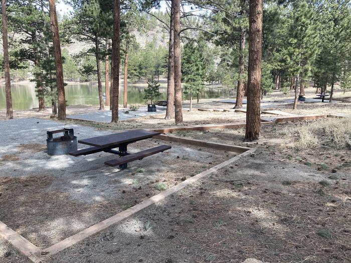 Campsite in the trees with picnic table and fire pit.A photo of Site 018 with Picnic Table, Fire Pit