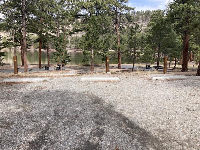 Campsite in the trees with gravel parking area, lake in background.A photo of Site 020 parking area.