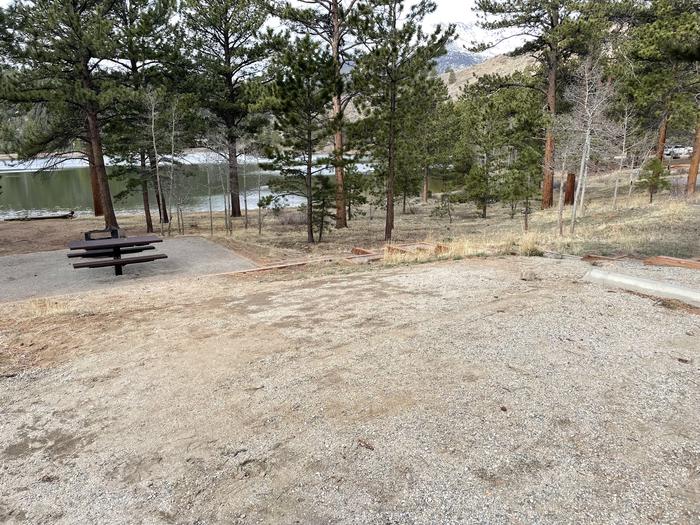 Campsite in the trees with picnic table and fire pit with lake in background. A photo of Site 029 with Picnic Table, Fire Pit