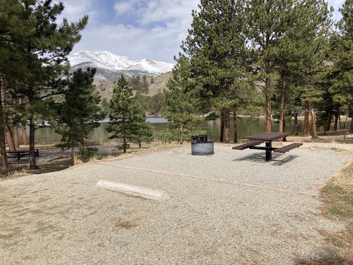 Campsite in the trees with picnic table and fire pit with mountain and lake in background.A photo of Site 022 with Picnic Table, Fire Pit