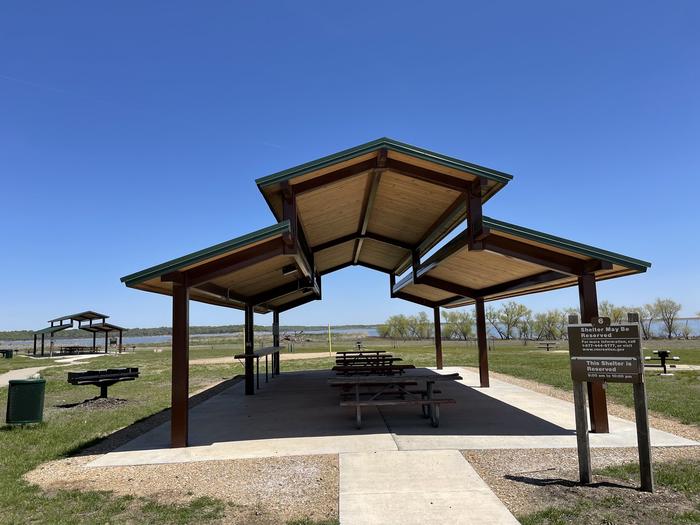 A photo of group shelter 6 in Bloomington East Park located at Bloomington East Swimming Beach. Includes shelter, tables, large grill, electric hookups, lighting, shared water spigot close by