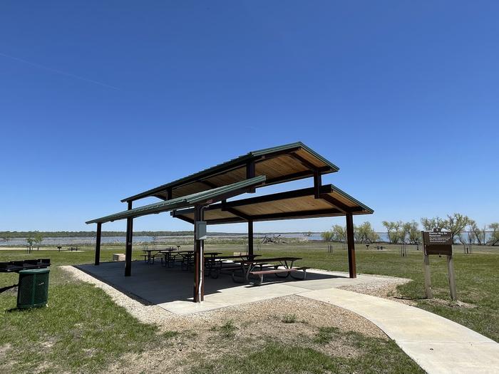 A photo of group shelter 5 in Bloomington East Park located at Bloomington East Swimming Beach. Includes shelter, tables, large grill, electric hookups, lighting, shared water spigot close by