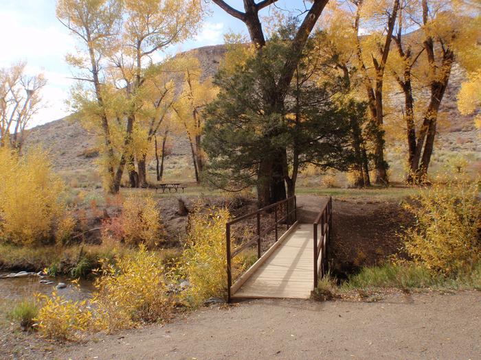 Bridge over creek in fall. Set in sagebrush and trees.Bridge to one of two tent areas.