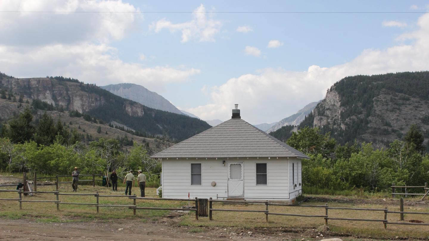 Cabin in moutainsSmall, white cabin surrounded by mountains, trees, and people