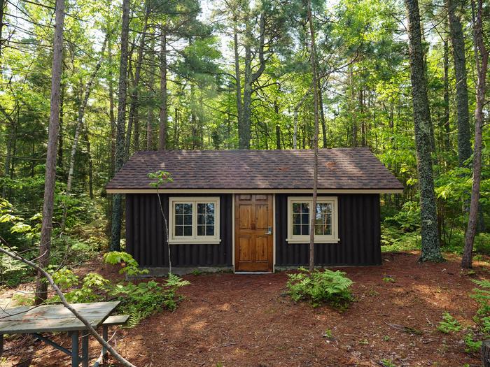 A log-cabin in the woods. Surrounded by a high forest.