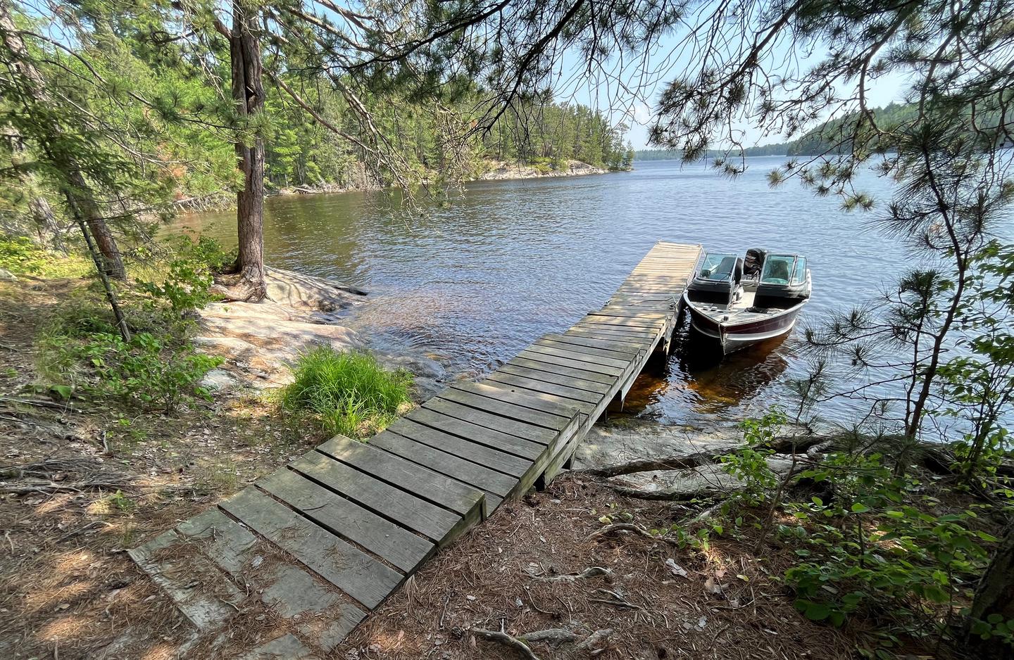 View of wood dock landing from shore with a boat tied to the dock.View of dock landing from shore.