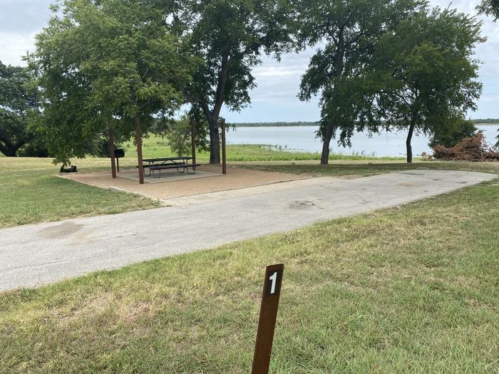 RV site with picnic table, grill, fire ring, and Waco Lake in the background