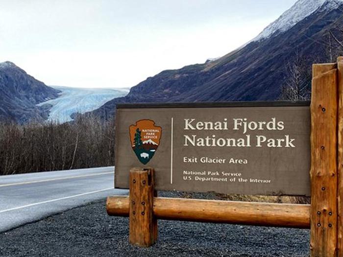 Kenai Fjords entrance sign on the road with Exit Glacier in the backgroundThe entrance to the Exit Glacier Area of kenai Fjords National Park.