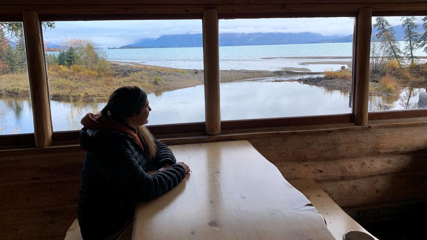 A lodger views Lake Clark through a window inside Priest Rock cabin